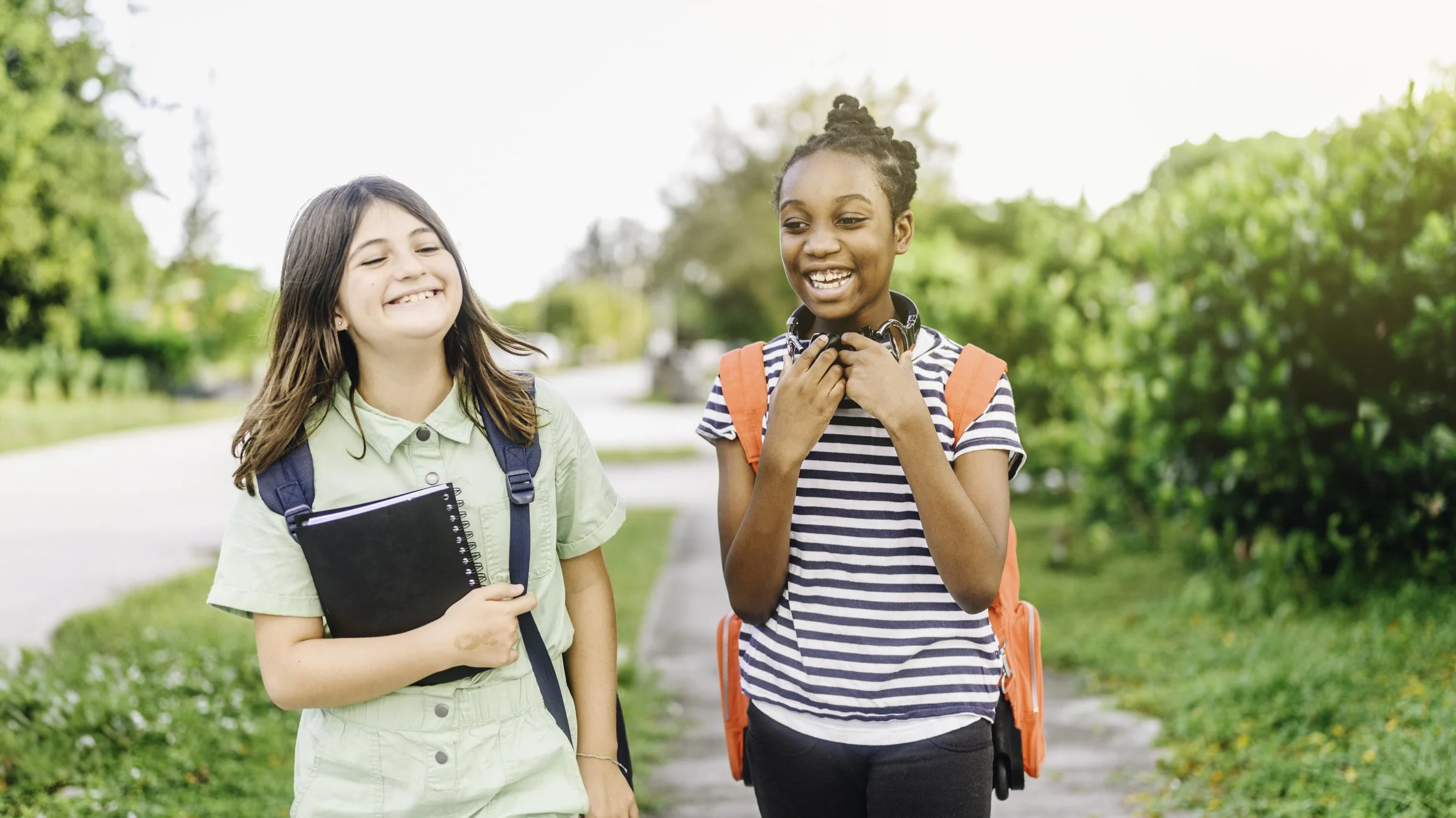 Two students with backpacks walking outdoors and talking together