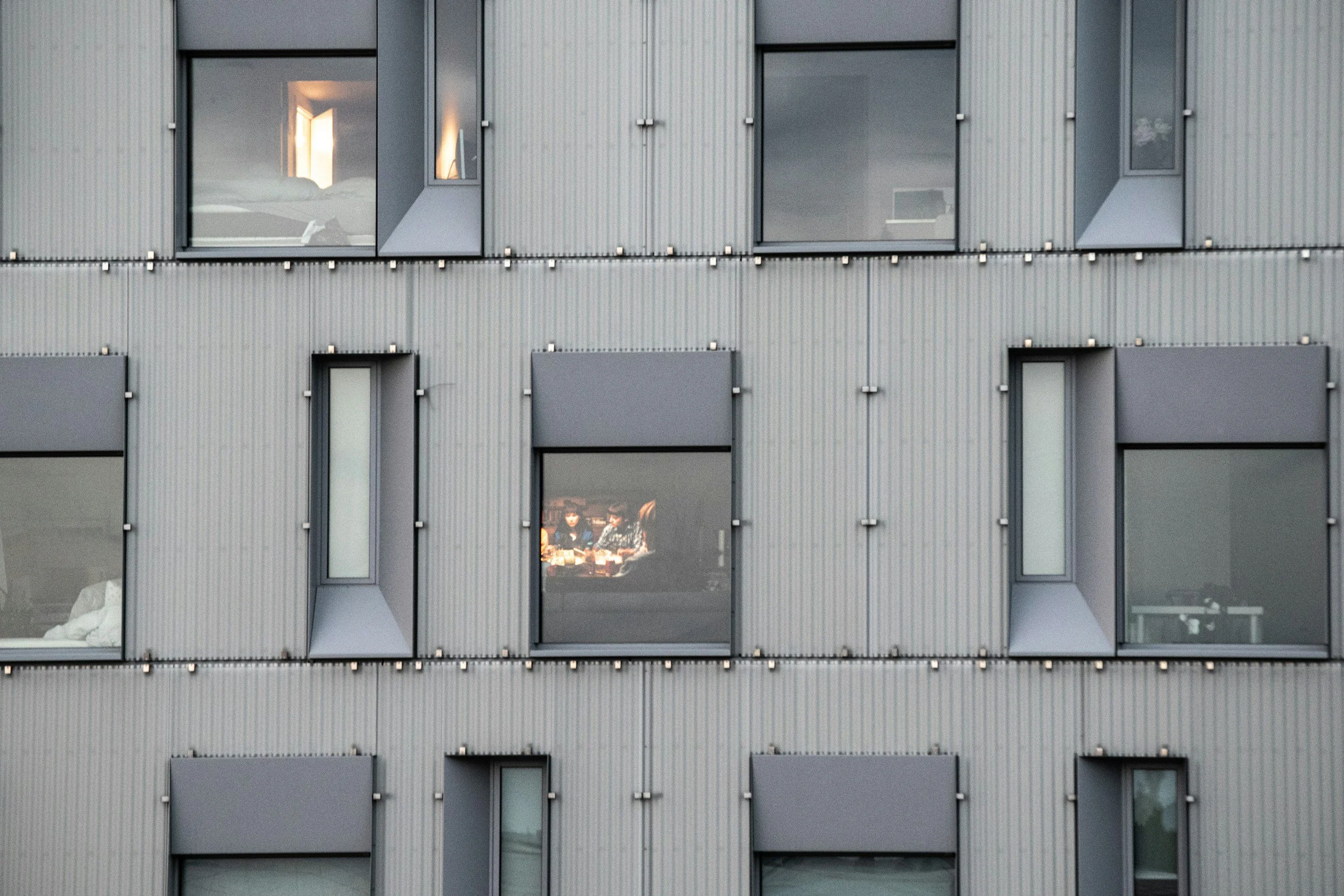 Fasad på en moderne bygning med flere vinduer og solskjerming.