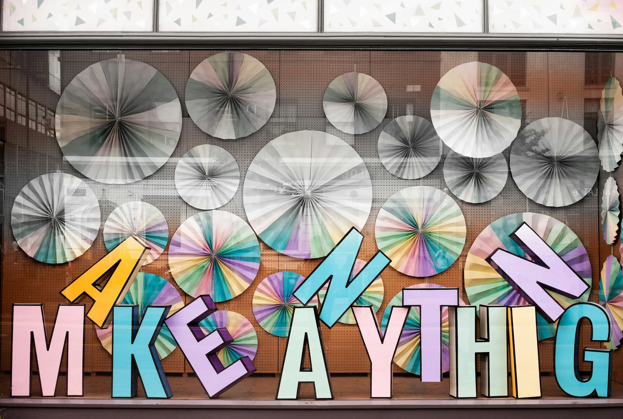 wall covered in colorful fans with jumbled words "make anything"