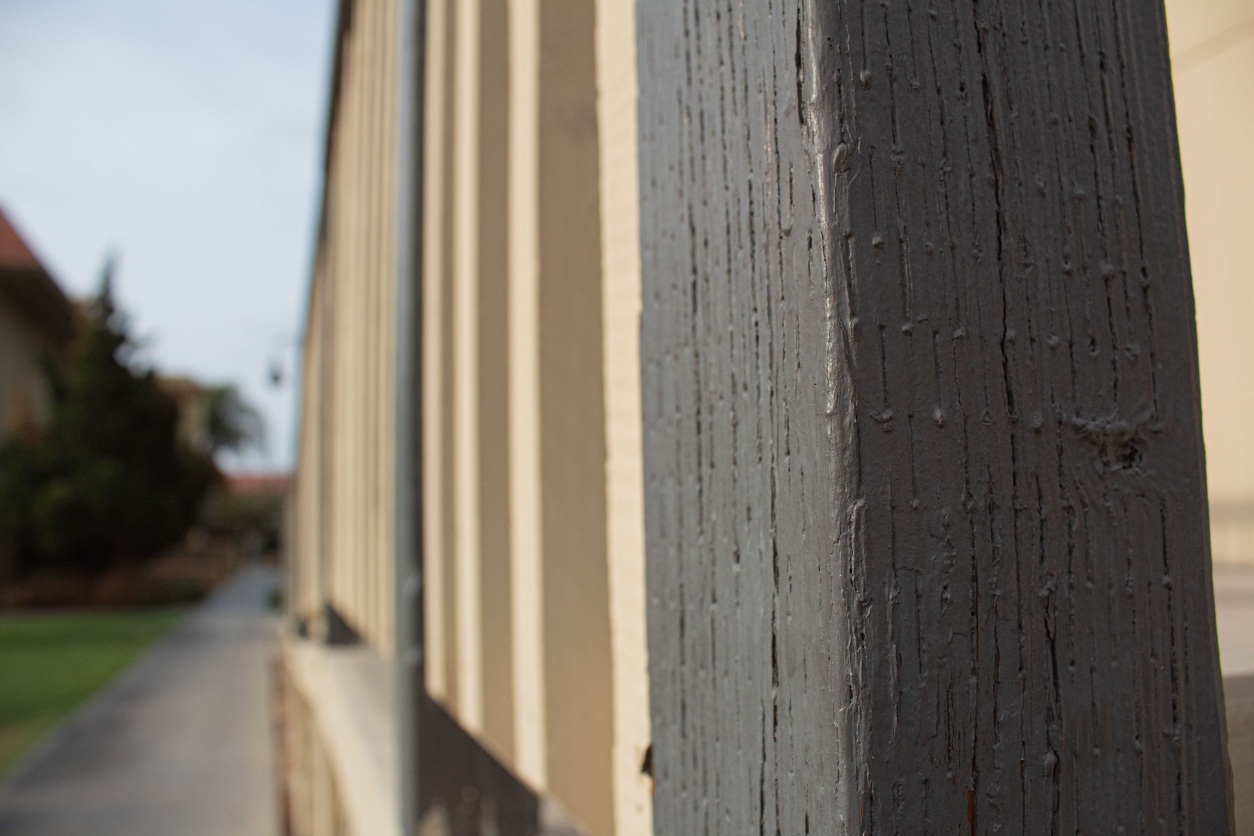 Close-up view of a black wooden fence post with a weathered surface, part of a row of similar fence posts.