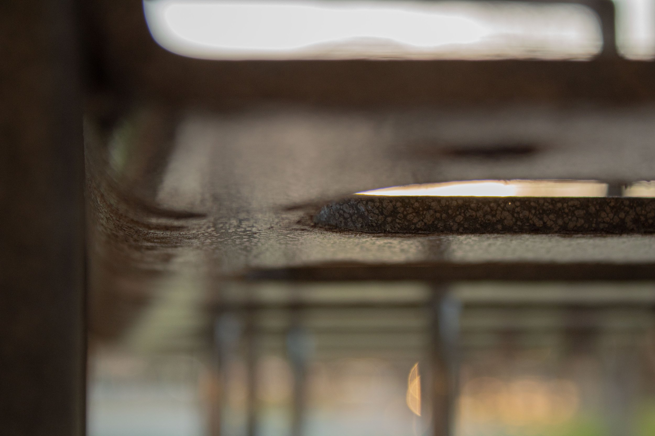 Close-up of a metal grate or drain cover, focus on the textured surface with blurred background.