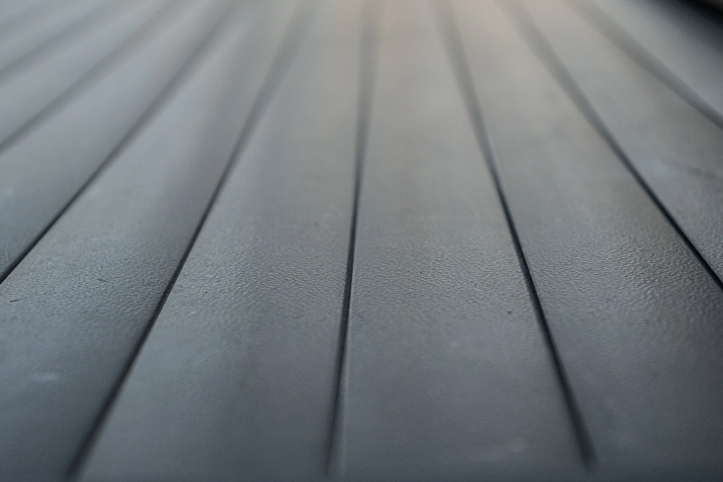 Close-up of a black textured rubber or plastic surface with parallel grooves.