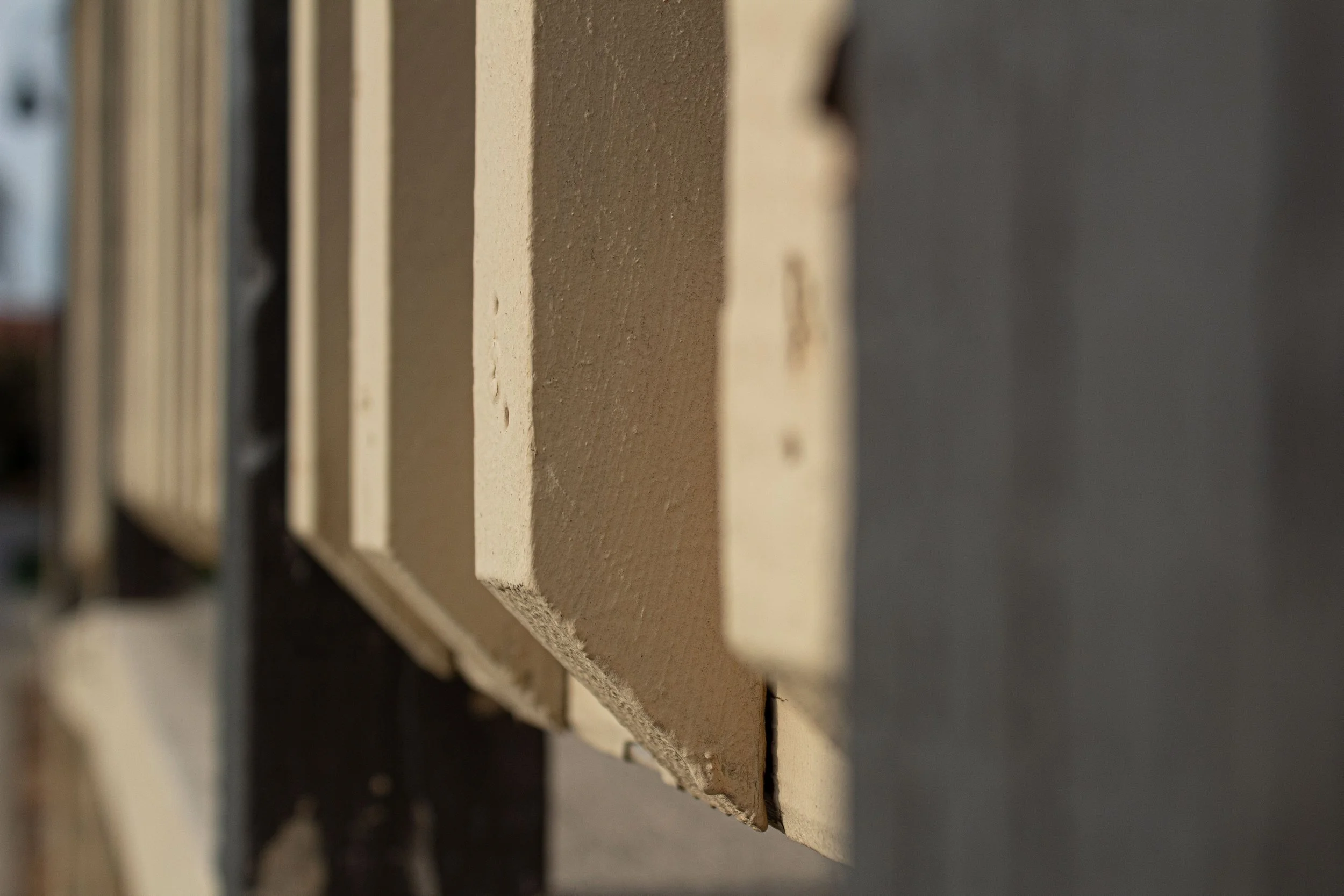 Close-up of a row of beige and gray painted wooden slats with visible textures, mounted on a vertical surface.
