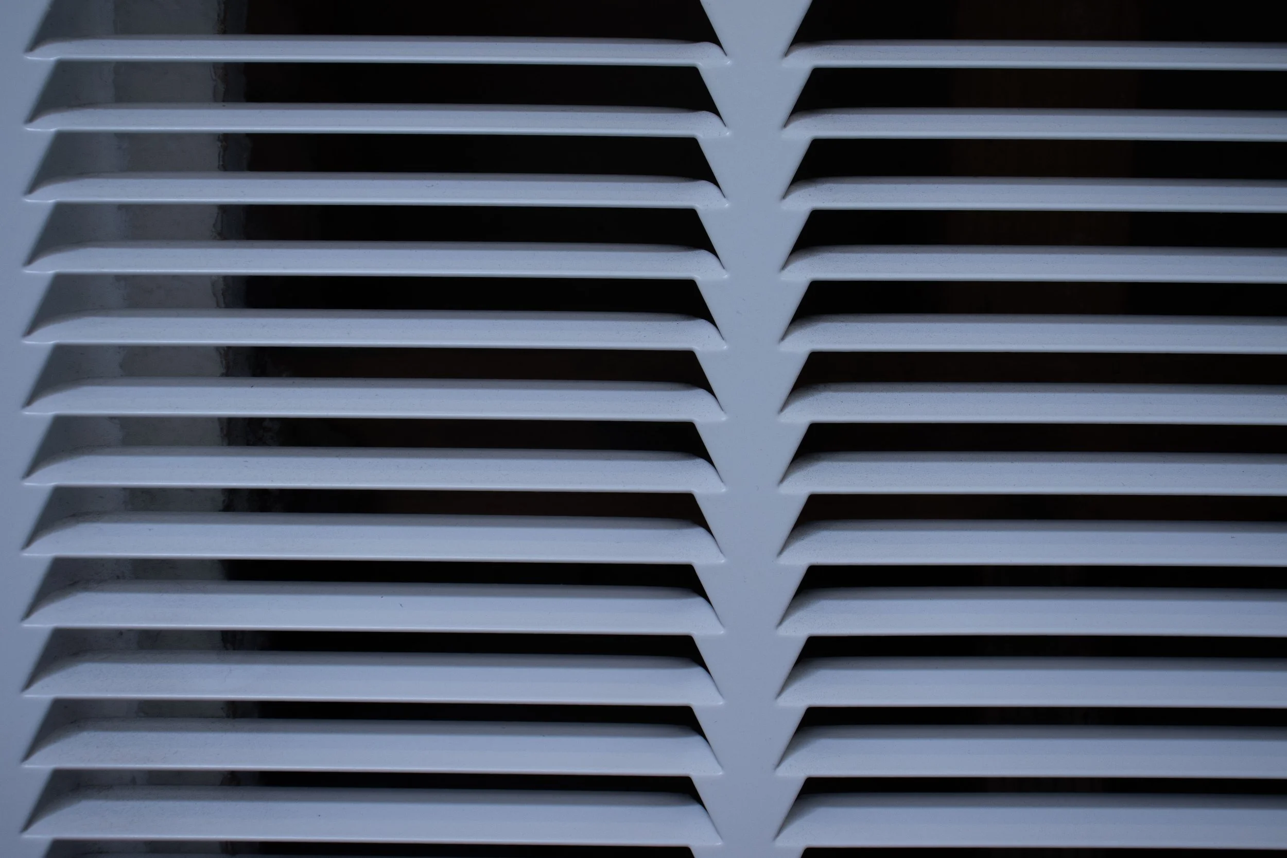 Close-up of white ventilation grille with horizontal slats.