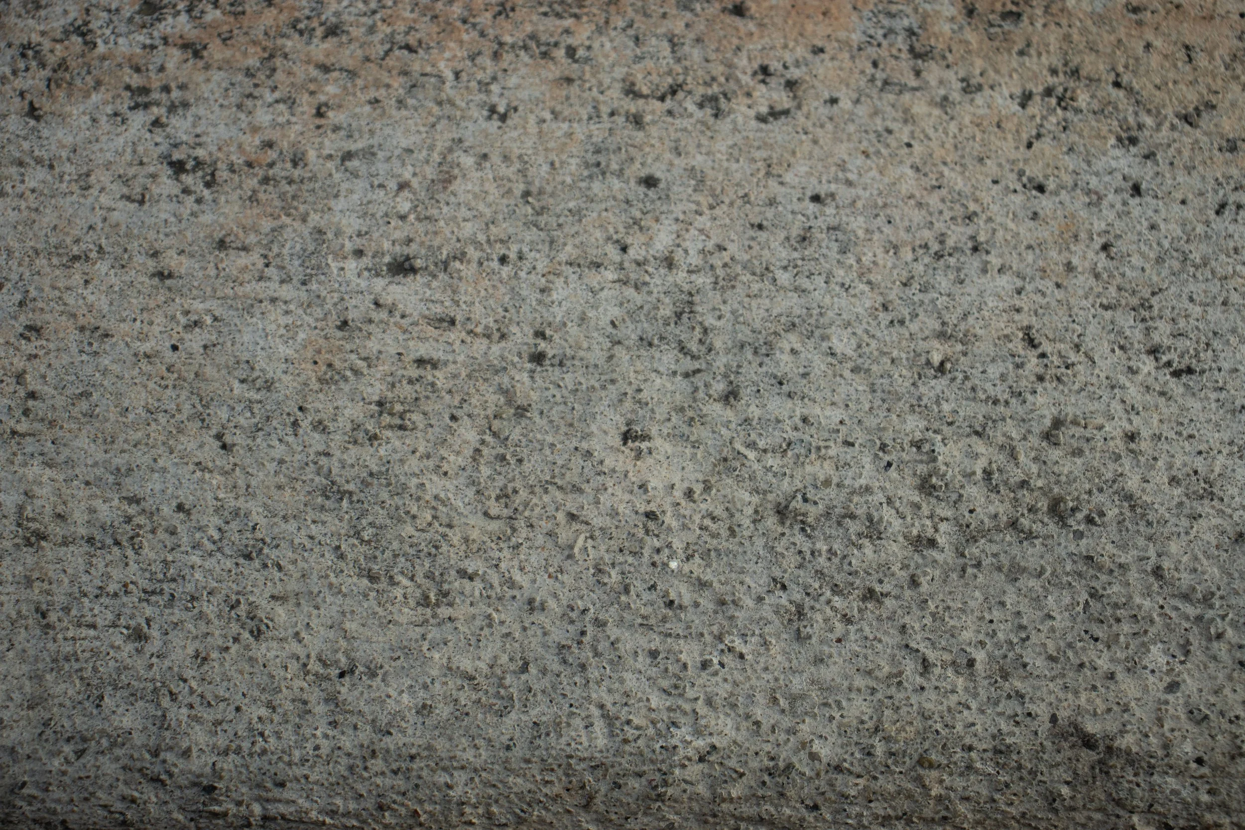 Close-up view of a textured concrete surface with small dark and light specks.
