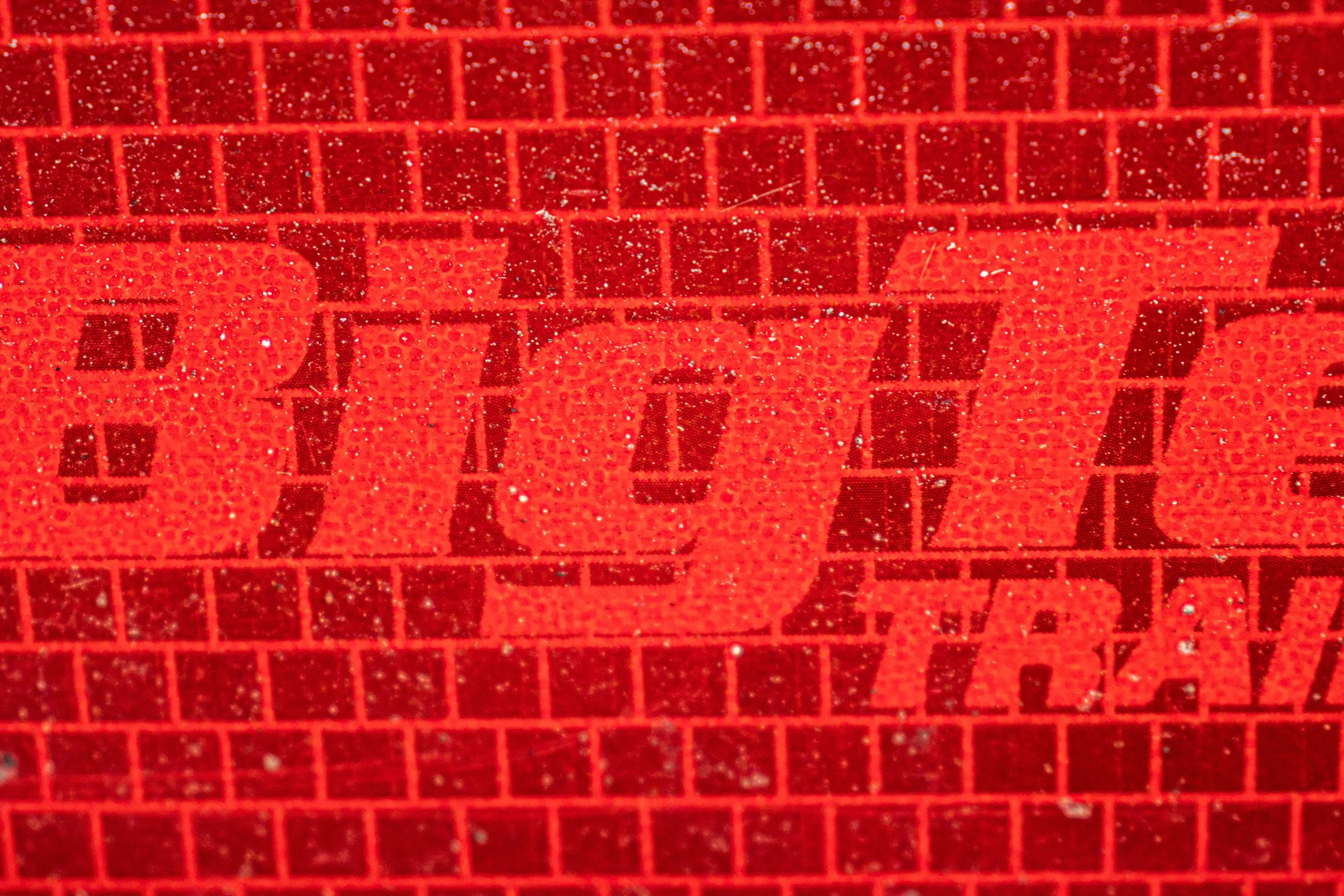 Close-up of red reflective surface with black text, likely part of a reflective sticker or label.