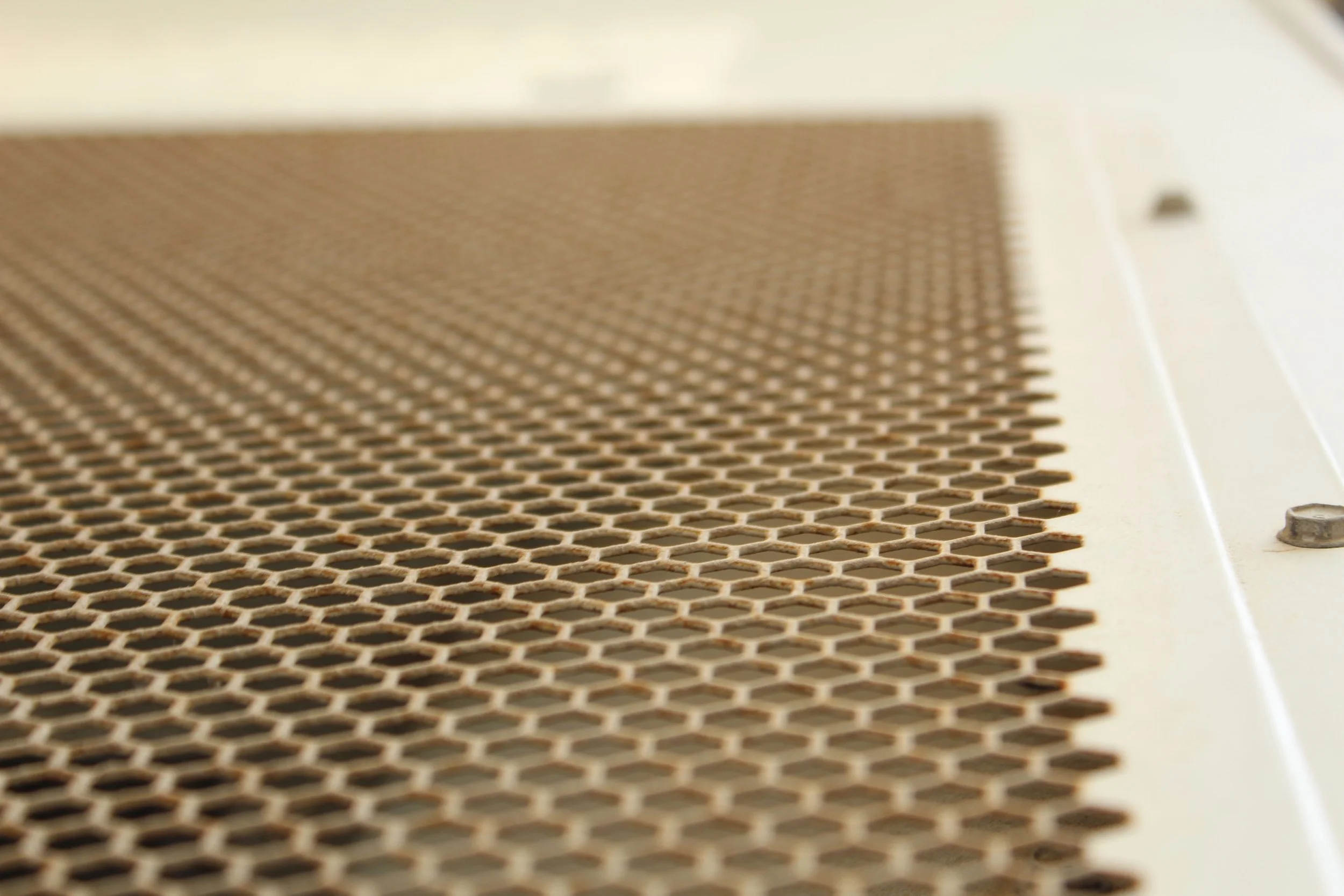 Close-up view of a perforated metal surface with a honeycomb pattern.