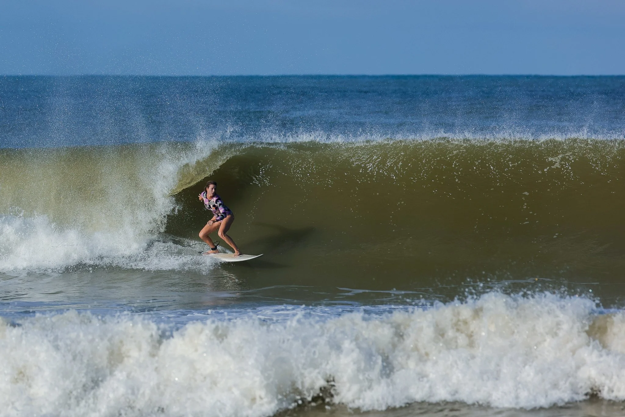 A woman surfing on a green wave in the ocean.