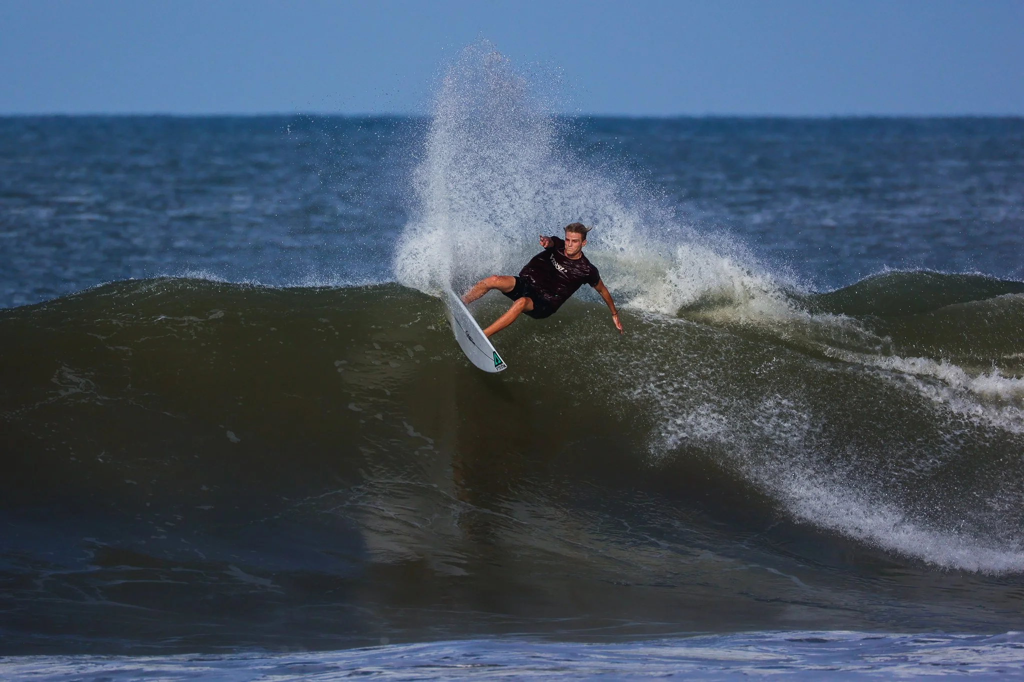 A surfer riding a wave on the ocean, with spray flying off the crest.