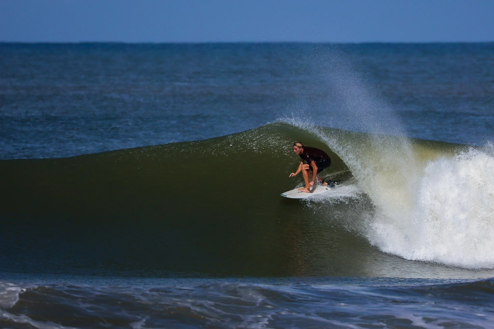 A person surfing on a wave in the ocean during daytime.