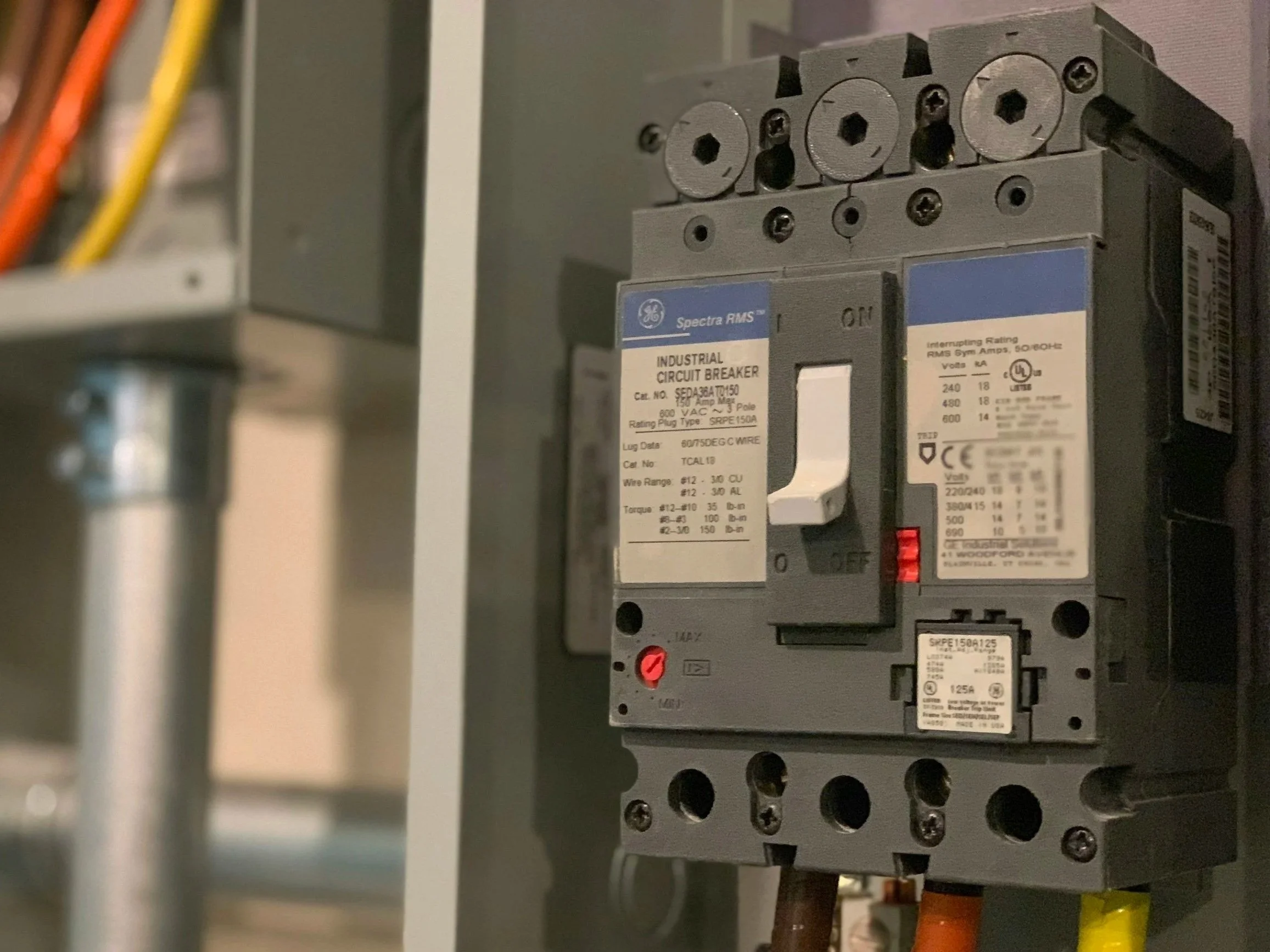 An industrial circuit breaker mounted inside an electrical panel with various wires connected.