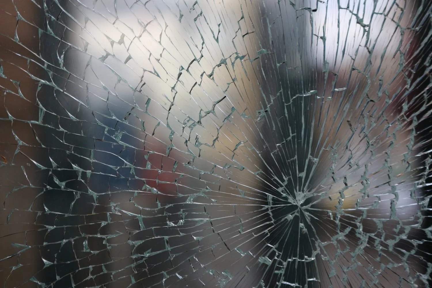 Close-up of broken glass with a spider web pattern of cracks for Glassworks emergency glass repair services.