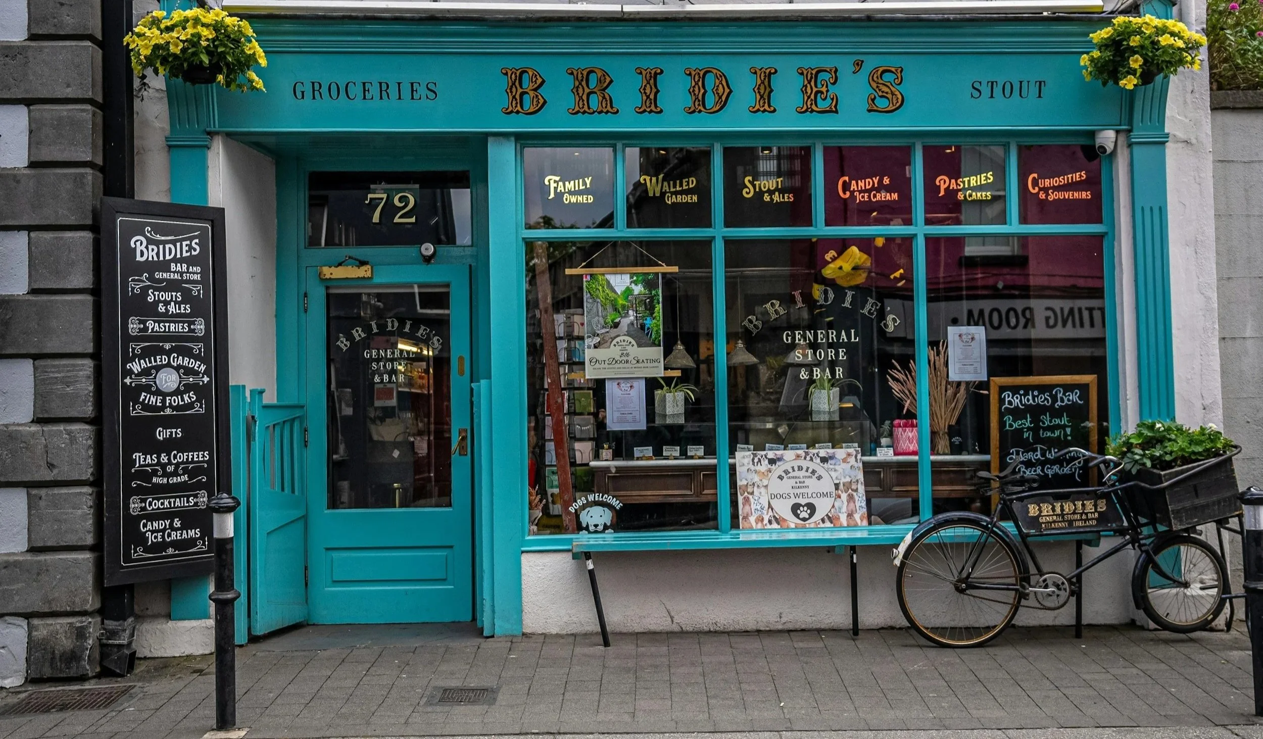 Front view of a small store called 'Bridie's' installed by Glassworks Houston with a bright blue facade, large display windows, and a bicycle parked outside.