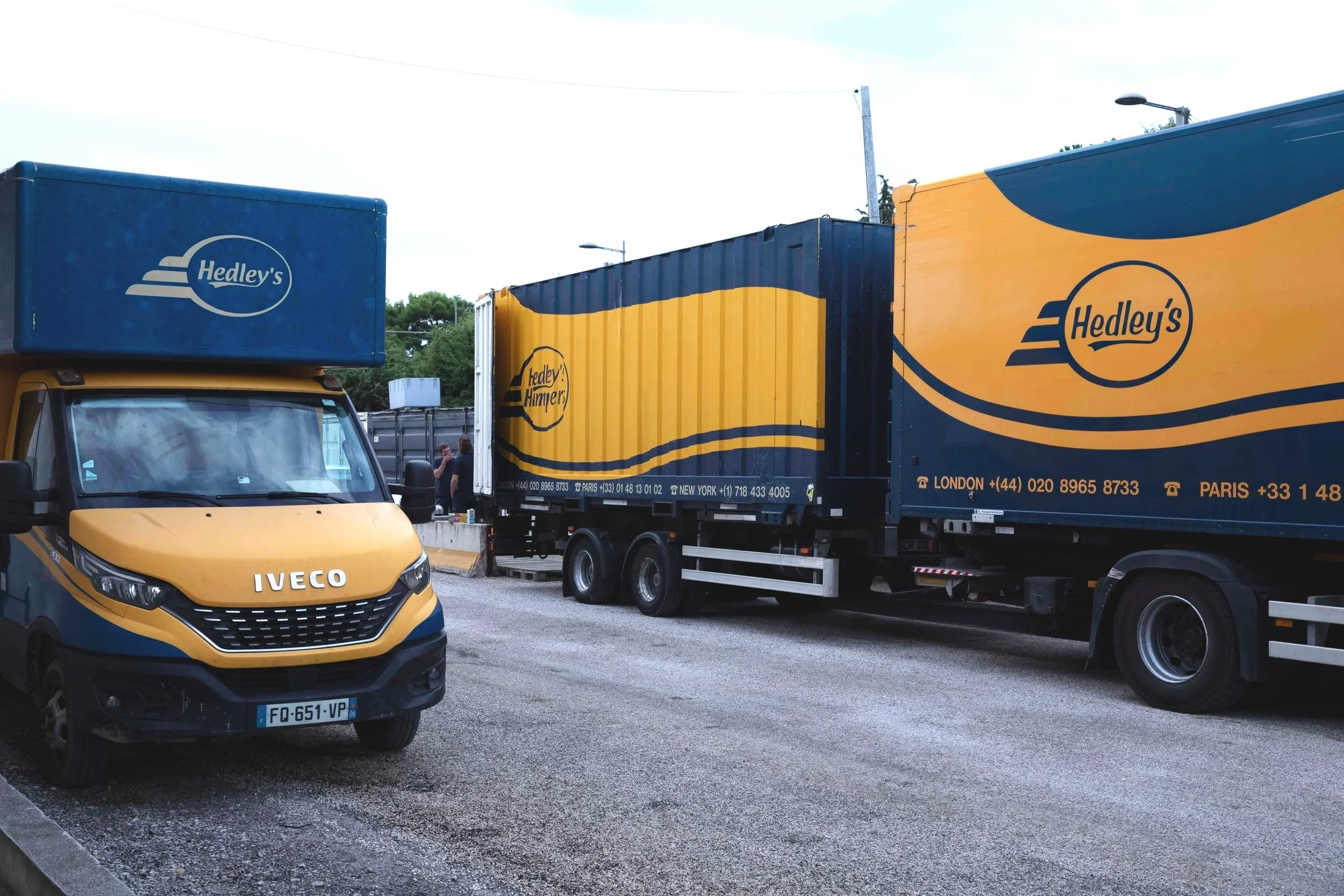 Deux camions de livraison Hedley's en bleu et jaune, avec une camionnette Iveco de couleur jaune et bleu色 sur une route
