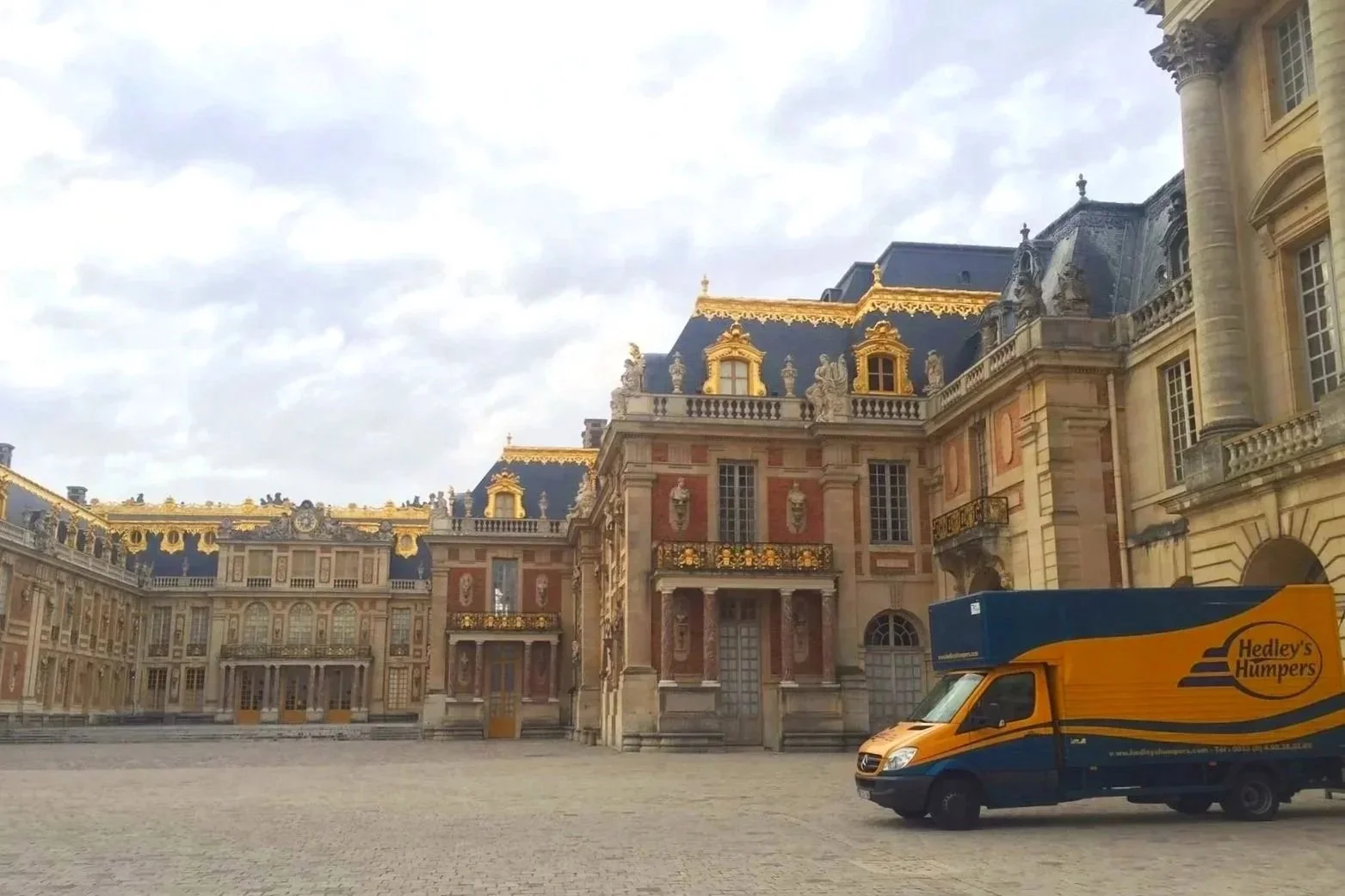 A historic palace with ornate architecture and gold accents, with a Hedley's Hampers delivery van parked in the courtyard.