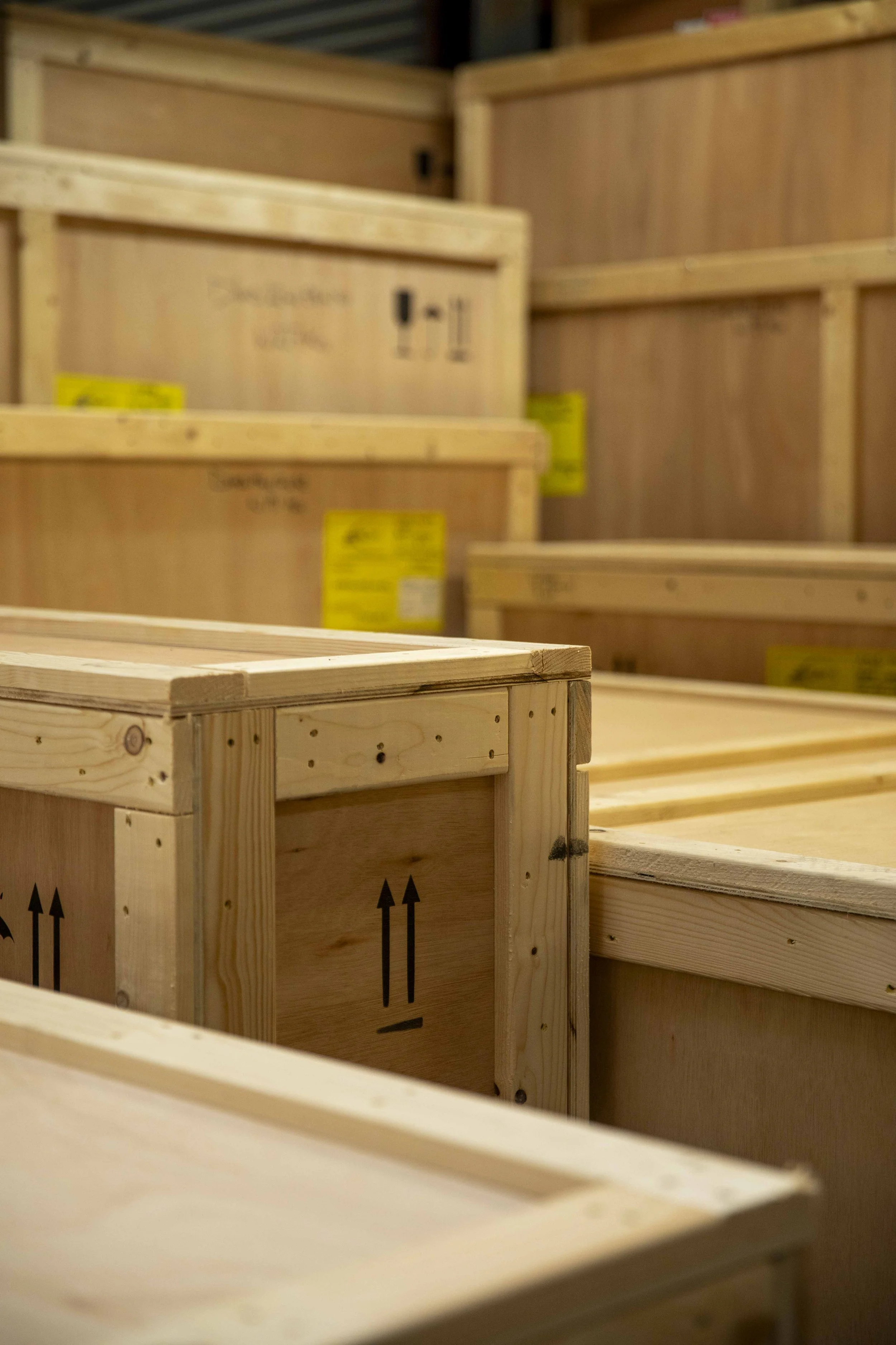Stacked wooden crates with black arrow symbols, in a warehouse or storage area.