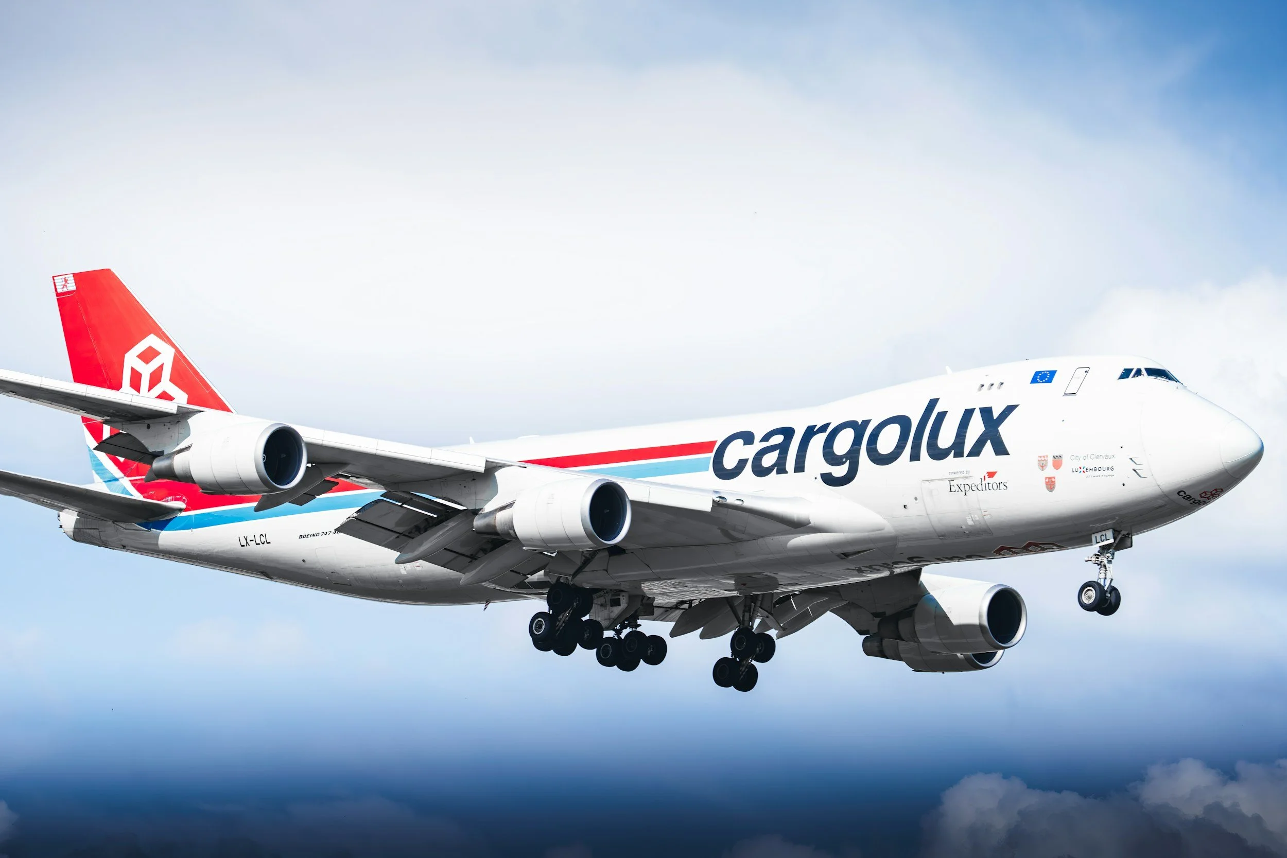Un avion cargo Boeing 747 de la compagnie Cargolux en vol, avec le logo de Cargolux sur le fuselage, contre un ciel nuageux.