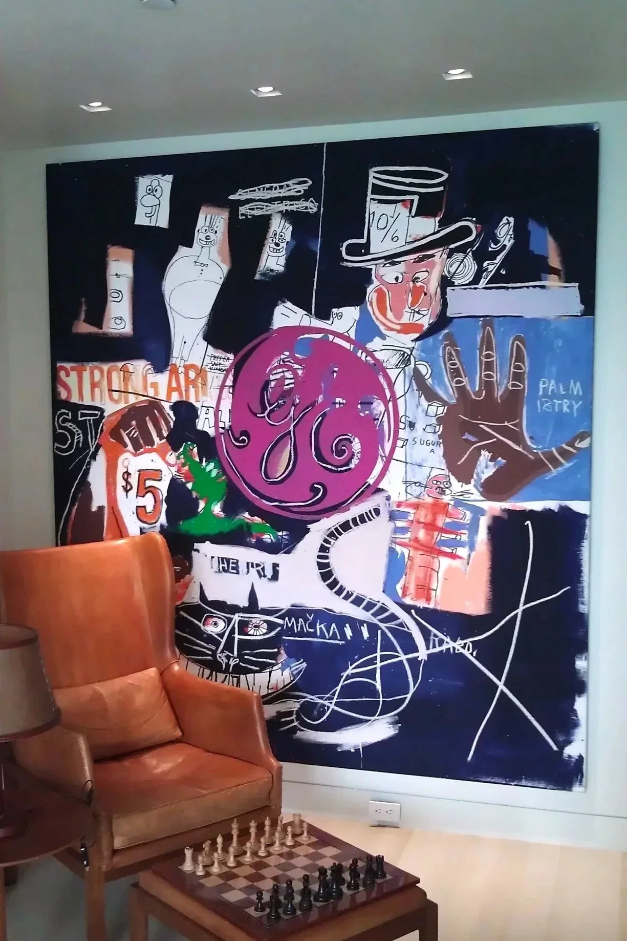 Peinture murale abstraite avec divers dessins et textes, dont un magicien avec un chapeau haut de forme, une main levée, une tête de chat, et des éléments colorés.