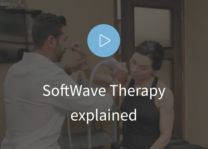 A healthcare professional demonstrating softwave therapy on a patient's arm in a clinic room.
