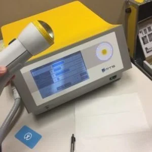 Medical device with touchscreen display and attached handheld scanner on a white countertop.