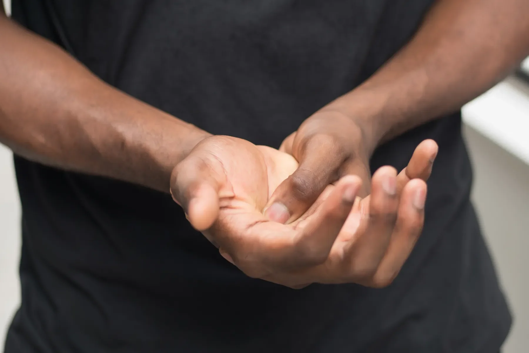 Two individuals shaking hands, one with dark skin and the other with light skin, in an indoor setting.
