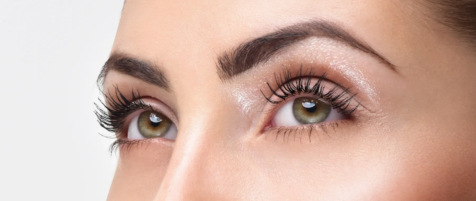 Close-up of a woman's face showing her eyes with long, curled eyelashes and well-groomed eyebrows.