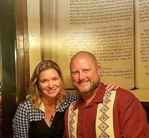 A woman and a man smiling and posing together in a restaurant or cafe.
