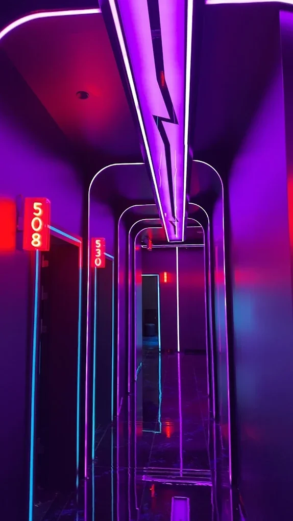 A futuristic corridor illuminated with purple and pink neon lights, featuring doorways numbered 508 and 530.