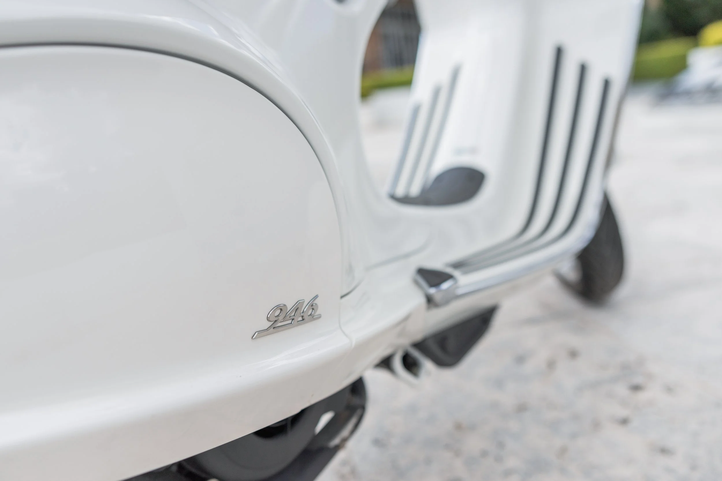 Close-up of a white vintage Vespa scooter with the model number '946' badge on the side.