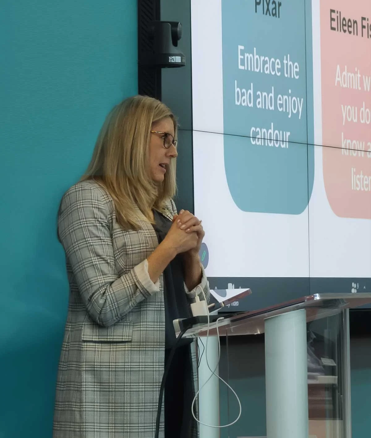 Keri Schwebius speaking at a podium in front of a large screen with a quote about embracing the bad.