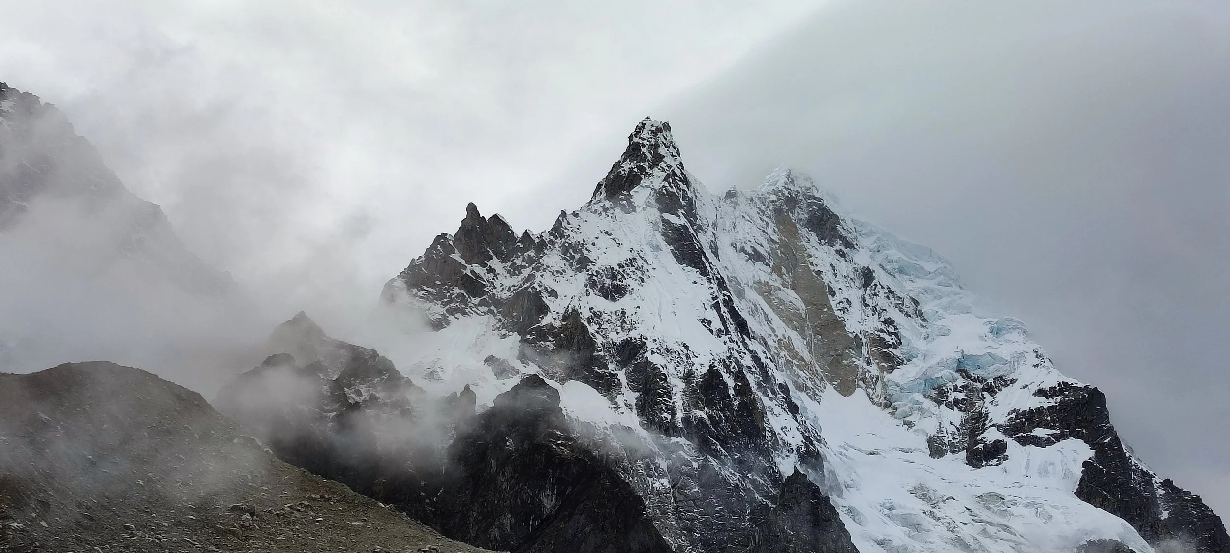 Snow-covered mountain peaks surrounded by clouds and mist.