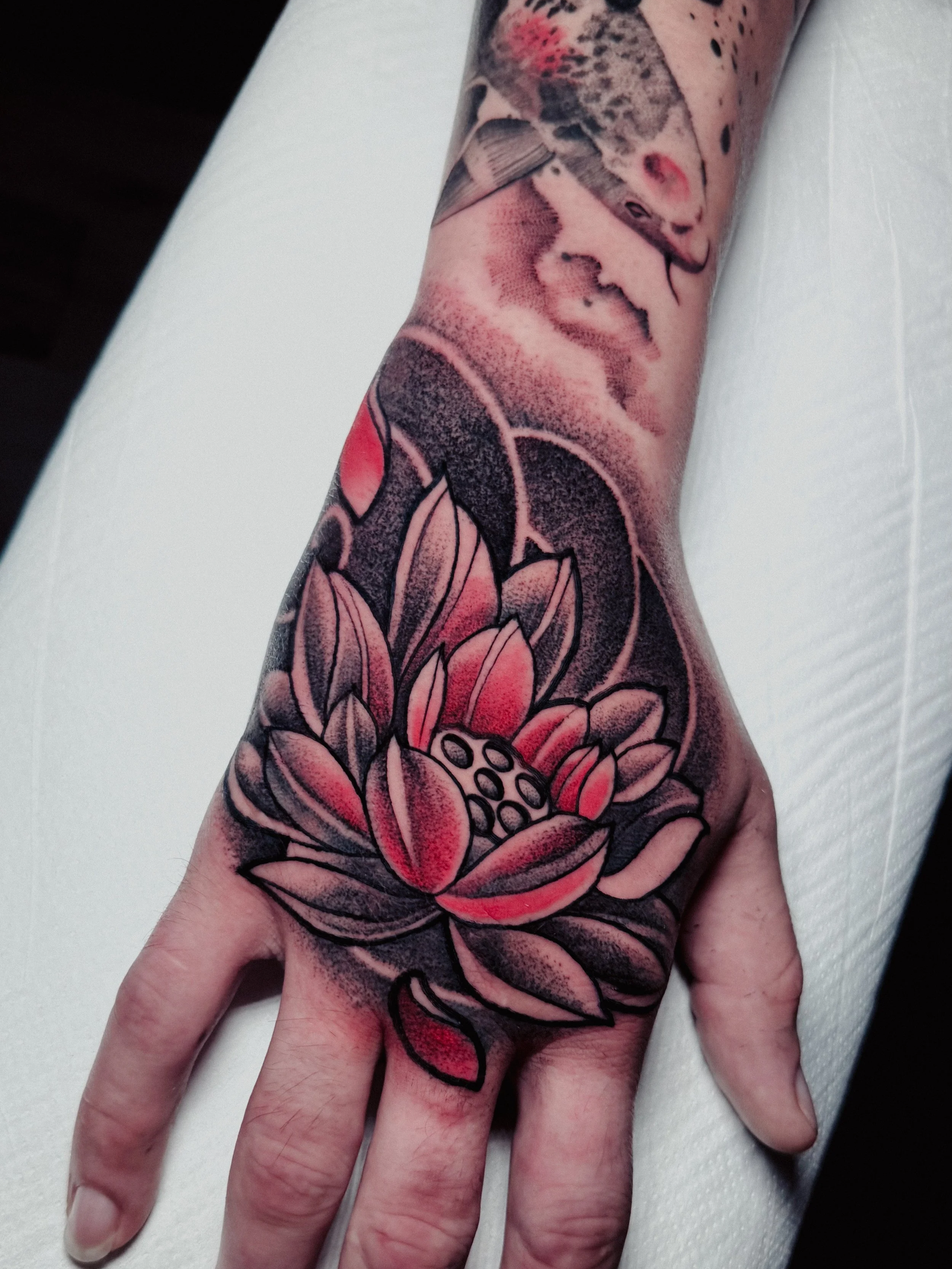 Tattoo of a woman's face and a pink lotus flower on a forearm.