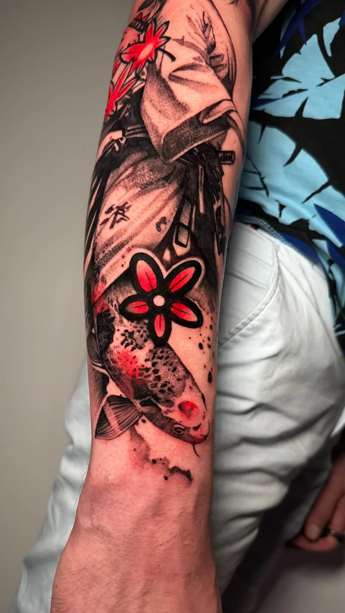 Tattoo of a fish with a flower on the forearm.