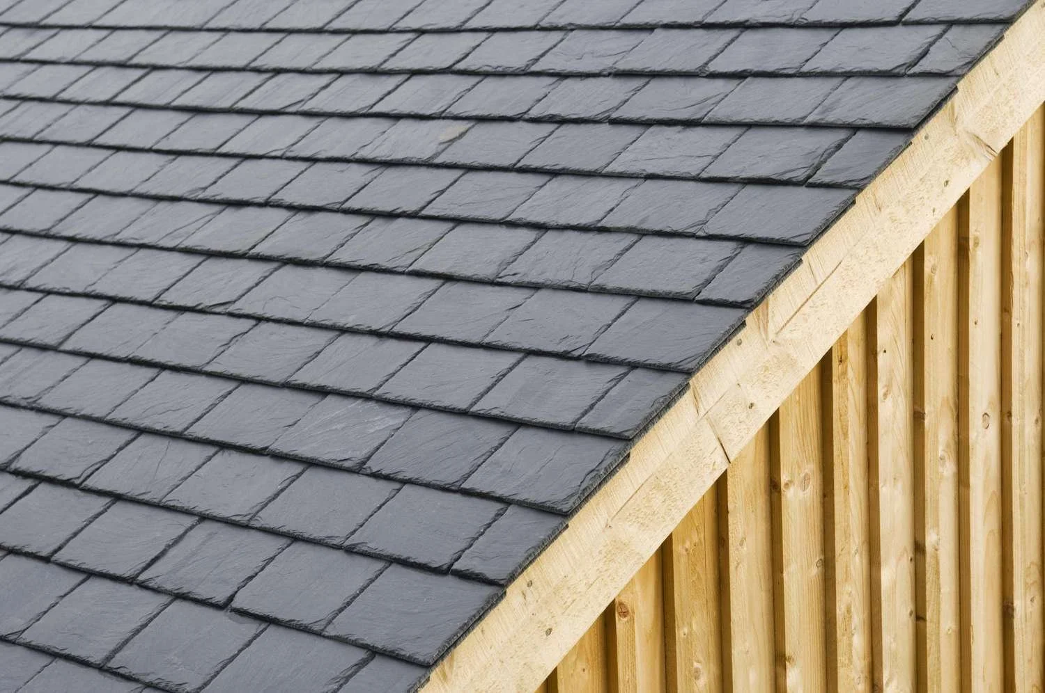 Close-up of a dark gray shingled roof with a wooden support structure underneath.