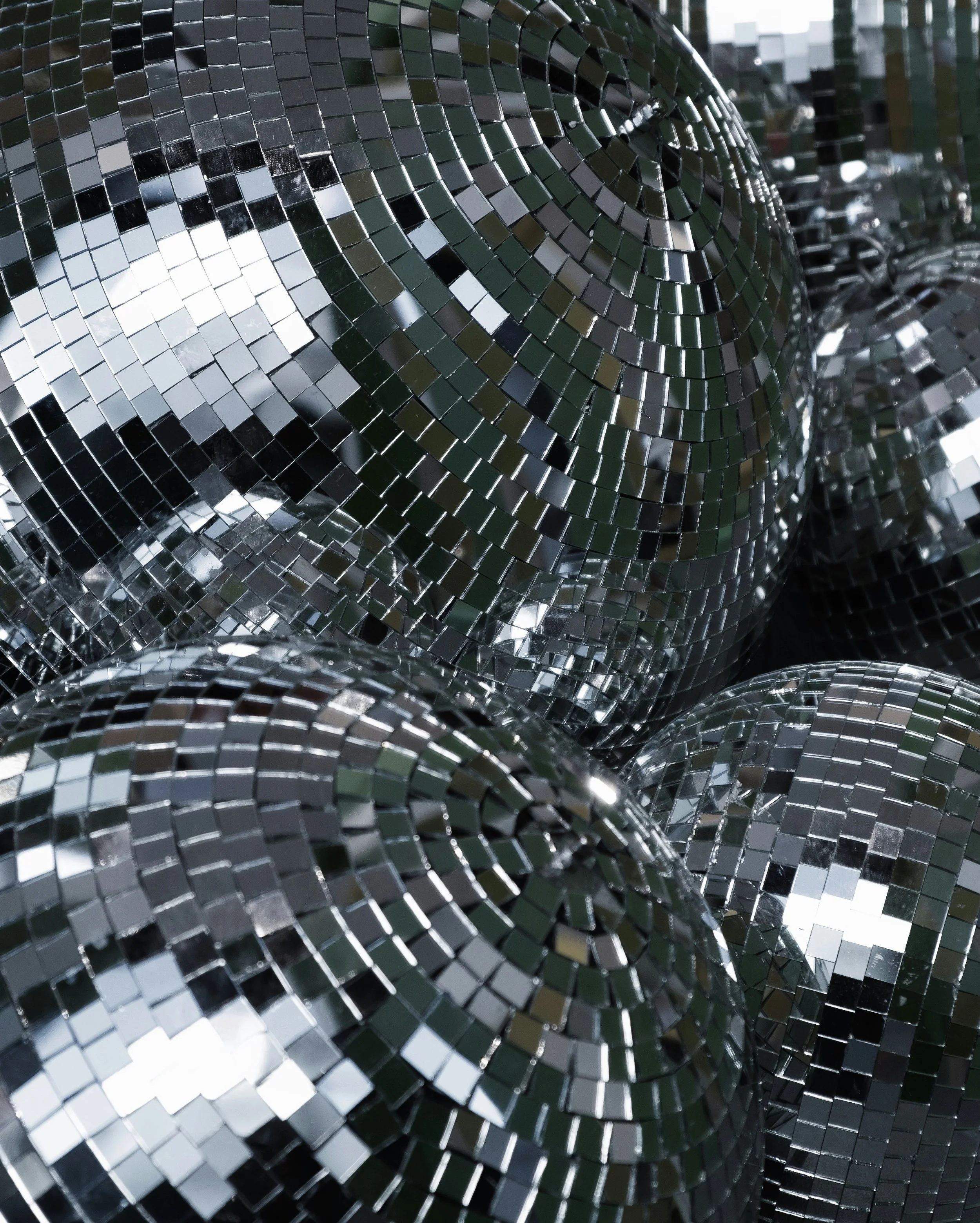 Close-up view of multiple rolls of mirror mosaic tiles with small square reflective surfaces in a spiral pattern.