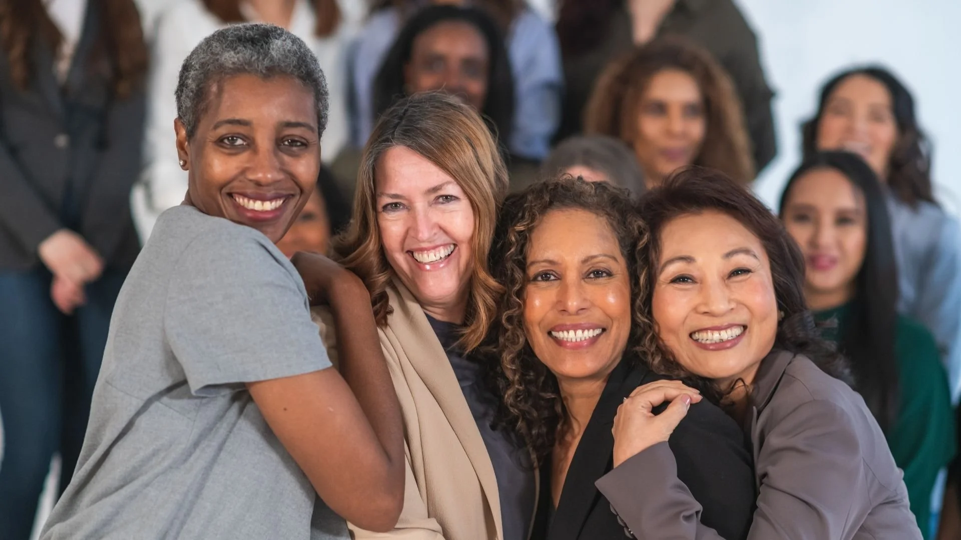 Group of diverse women smiling and hugging at a social gathering.