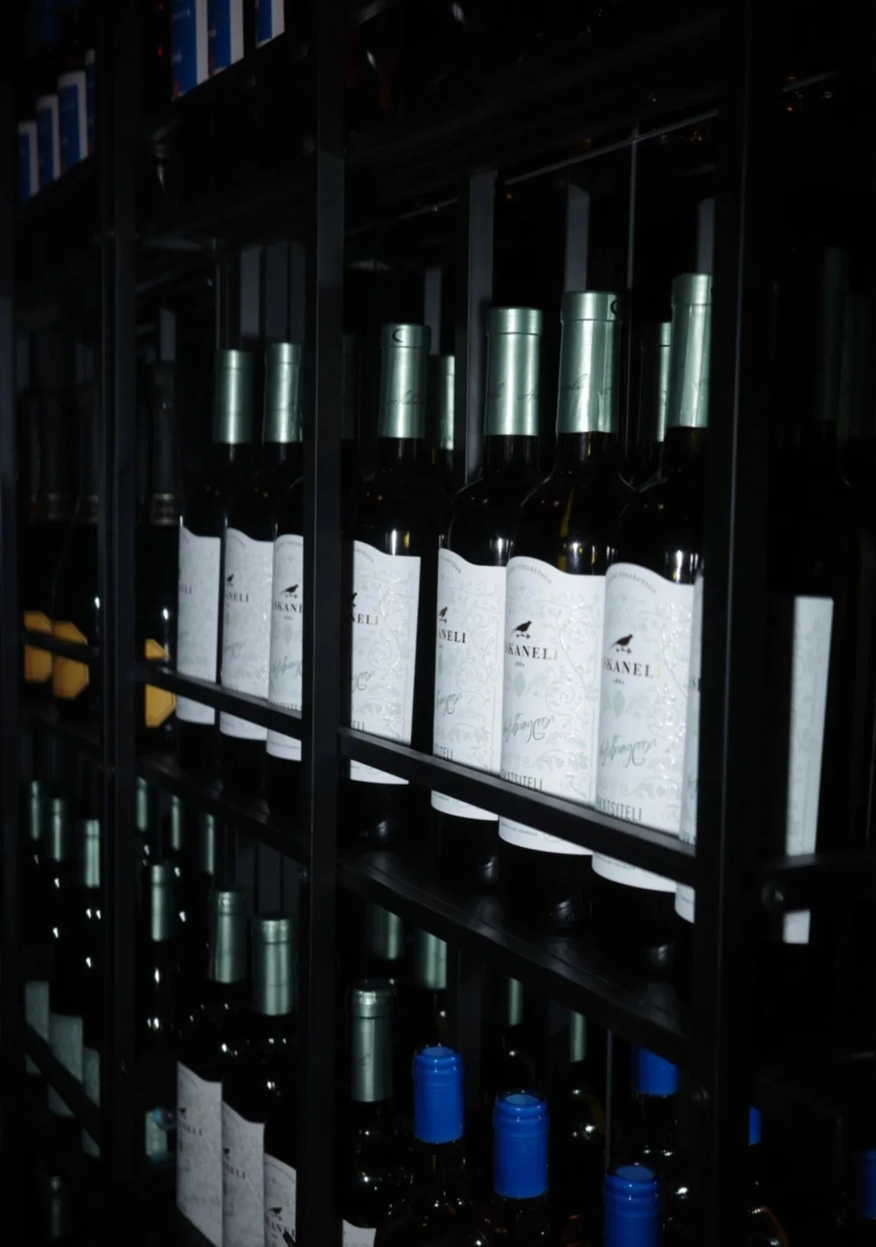 Shelf of wine bottles in a wine cellar with metal racks.