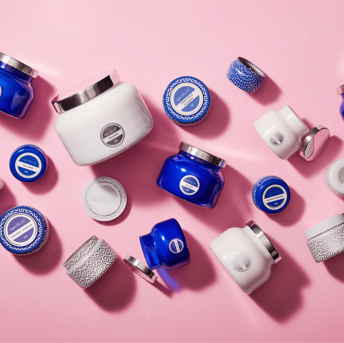 Assorted blue and white jars of body butter or skincare products on a pink surface.