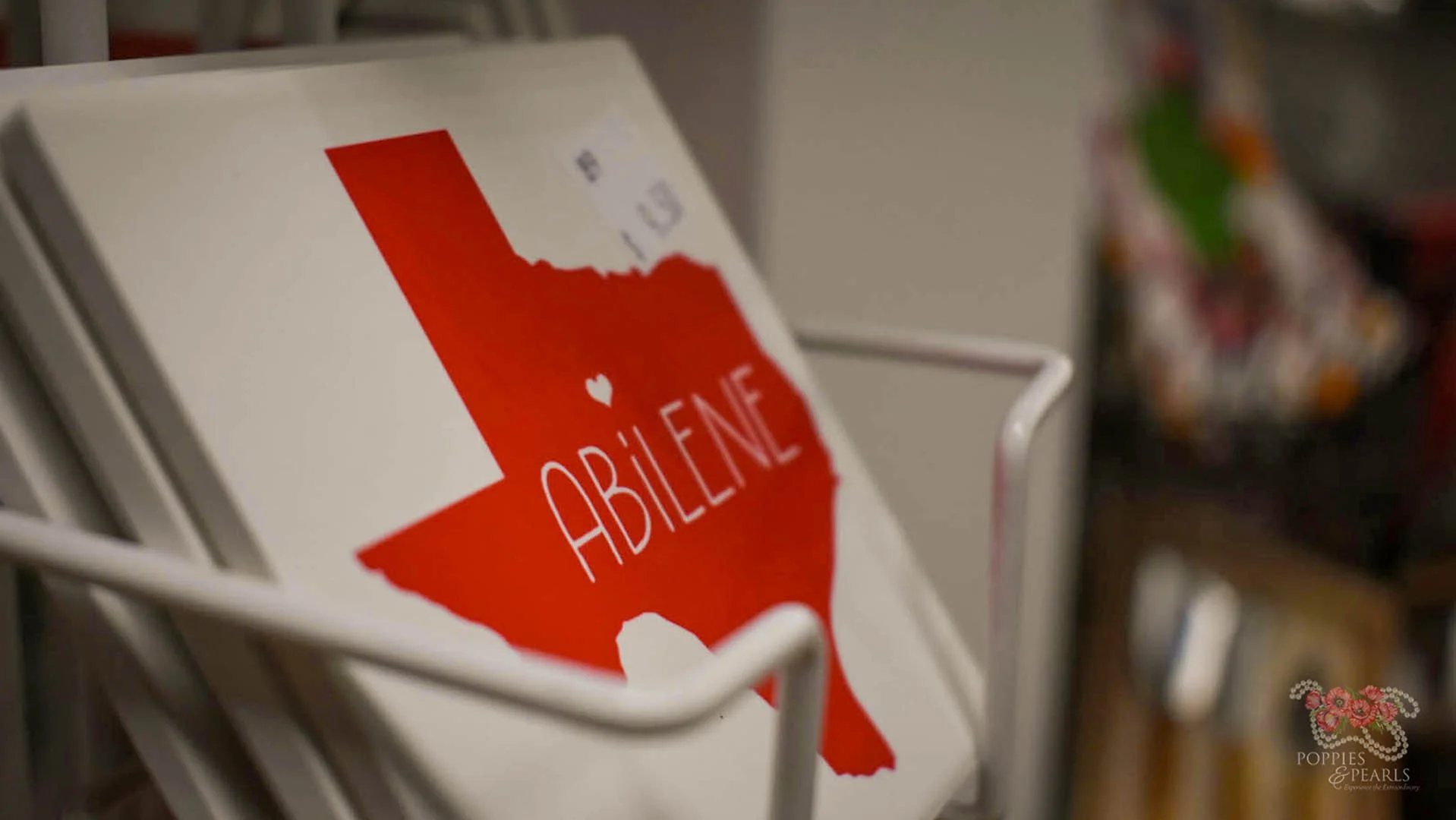 A card with the shape of Texas and the word 'ABILENE' printed in white, placed in a white wire basket.