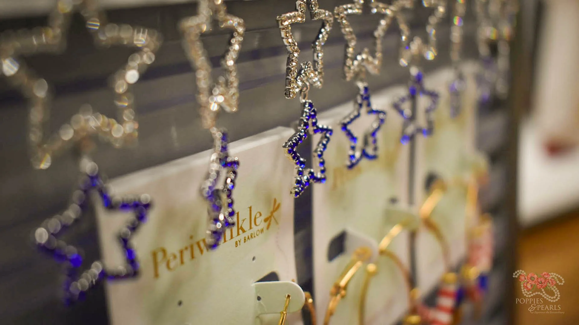 Close-up view of star-shaped earrings hanging on display hooks, some with blue and silver details, on a jewelry display board.