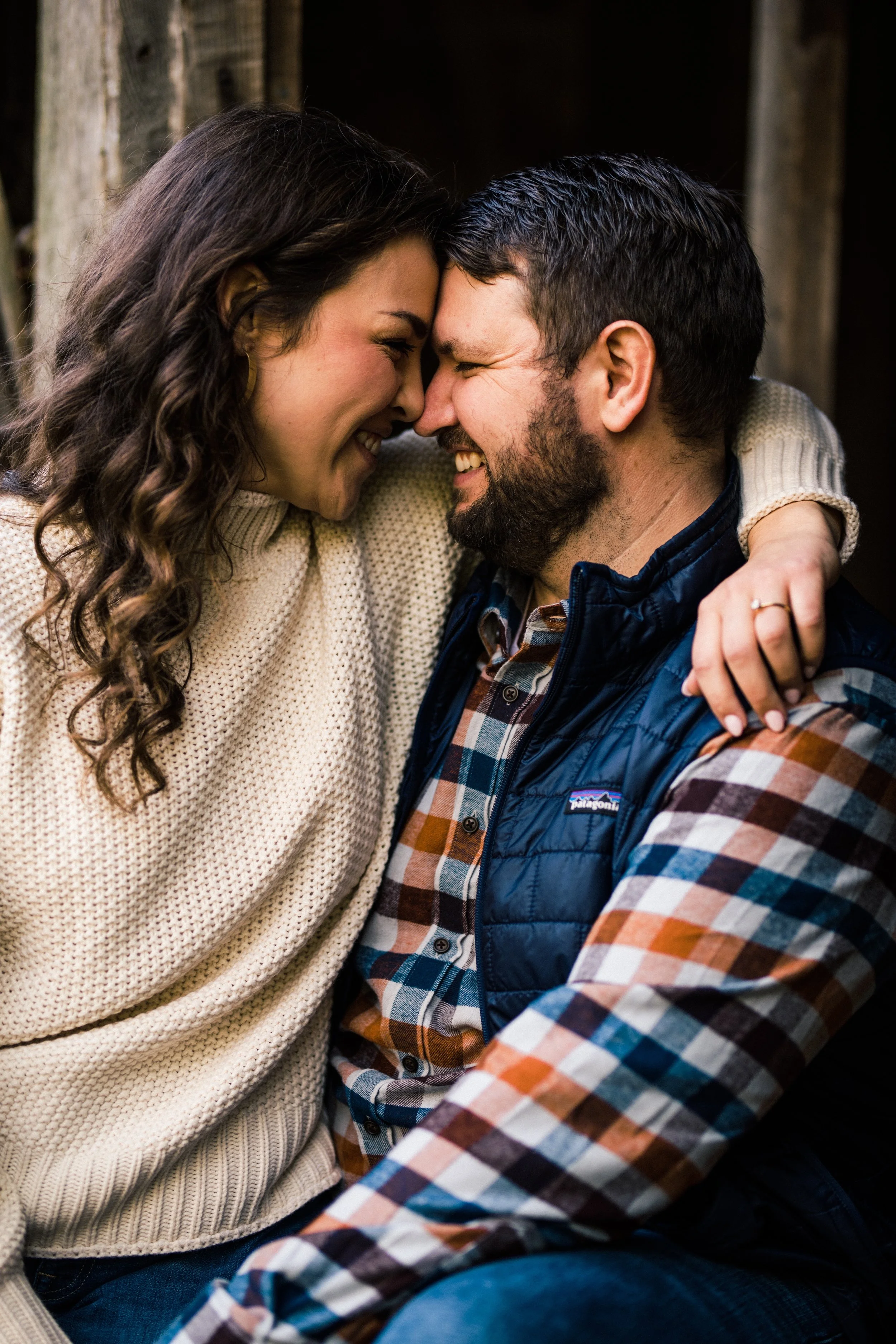 A woman and a man with their foreheads touching, smiling, in an outdoor setting.