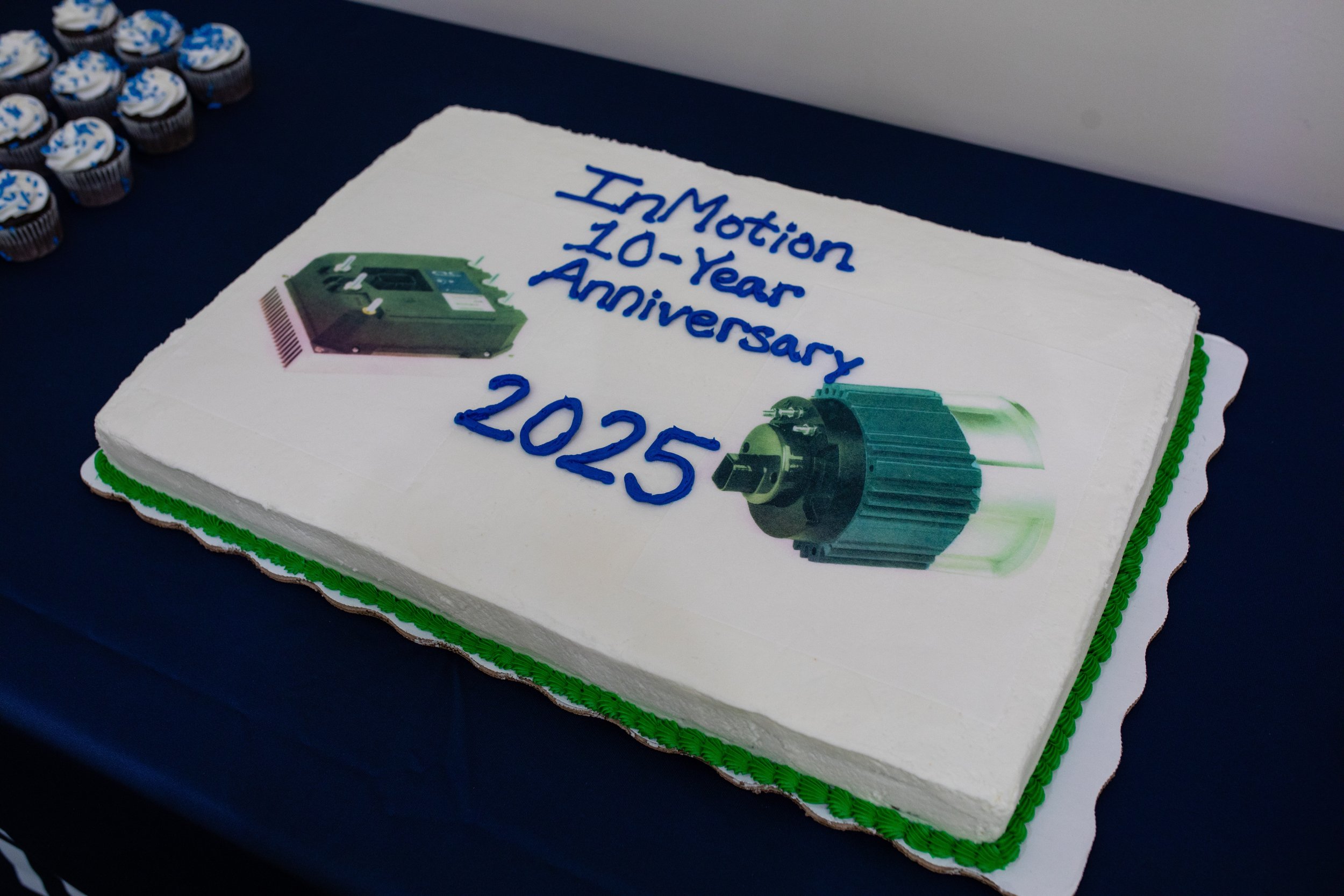 A decorated cake celebrating the 10th anniversary of InMotion, featuring images of a hard drive and a mechanical component, with blue writing on a white background that says 'InMotion 10-Year Anniversary 2025'.