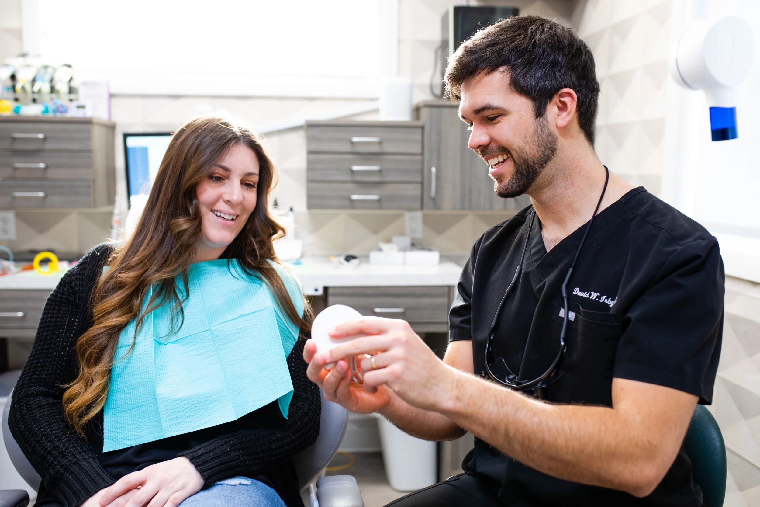 Dentist showing a dental model to a female patient in a dental clinic.