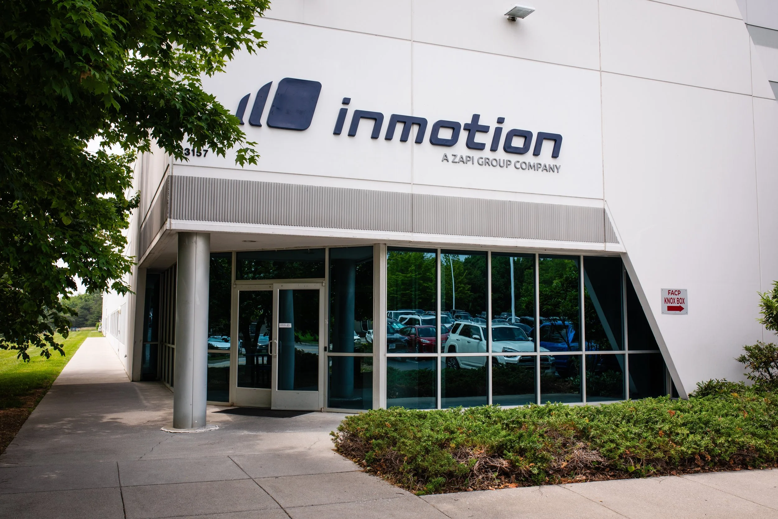 Exterior of a modern office building with large glass windows and a sign that reads 'immotion, a ZAPI GROUP COMPANY'.