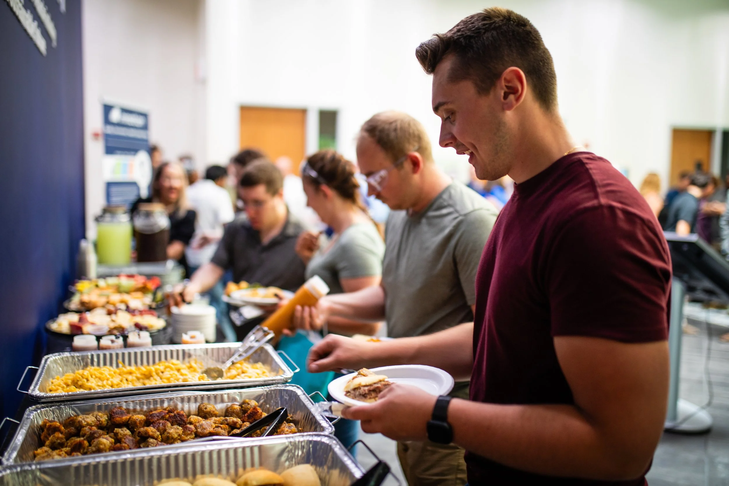 People serving themselves food at a buffet table during an event.