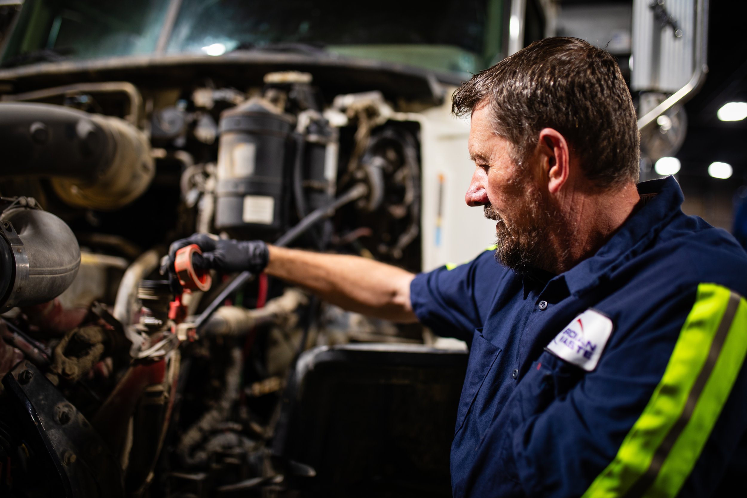 A mechanic working on a truck engine in a workshop.