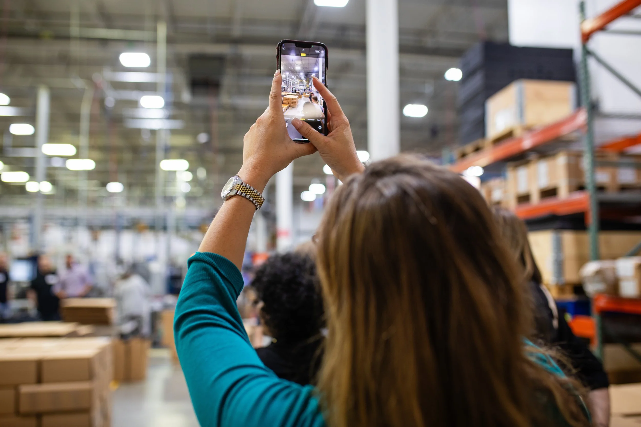 Person taking a photo with a smartphone in a warehouse or store setting.