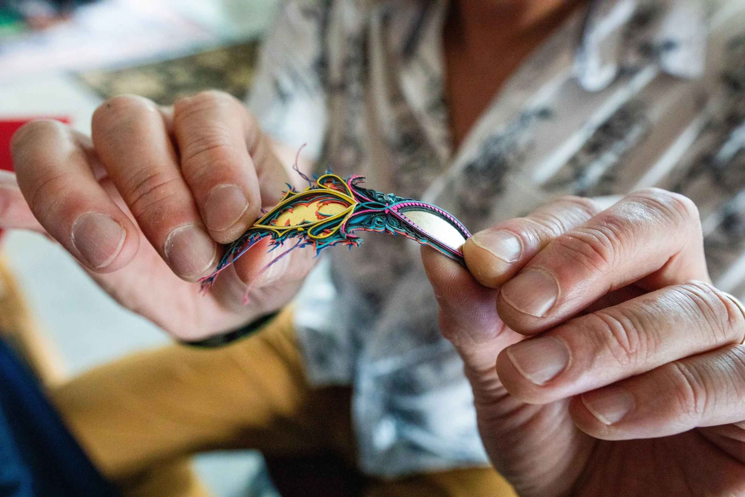 Close-up of a person weaving colorful paper strips into a decorative design with their hands.