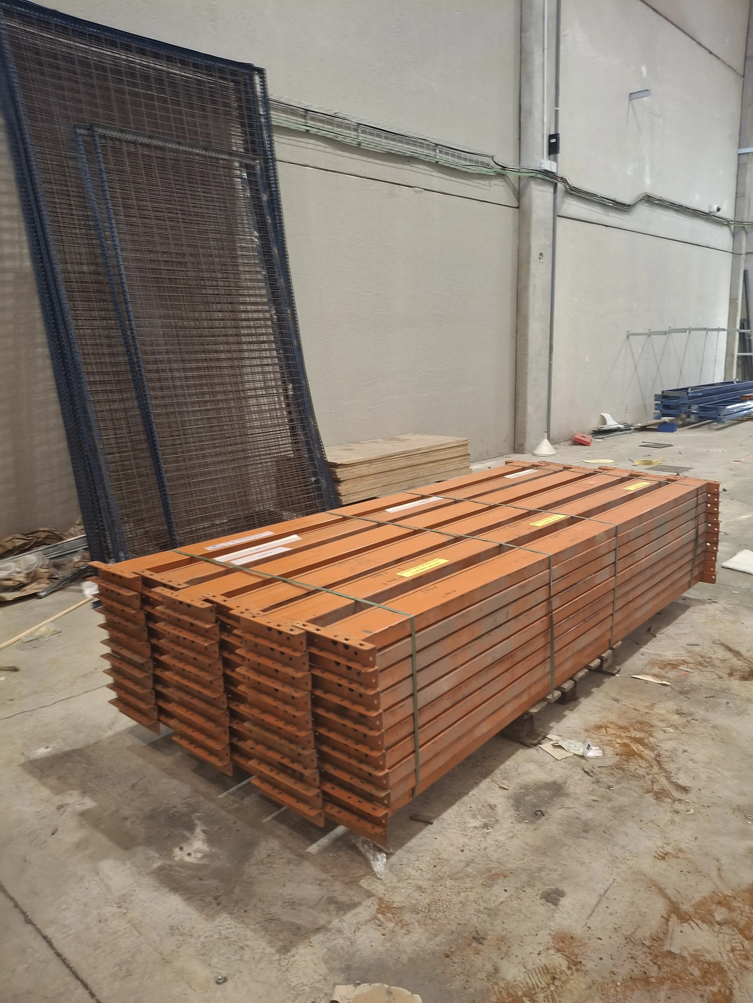 Estantes y tablas de madera, estructura metálica y materiales de construcción en un espacio de construcción o almacén.
