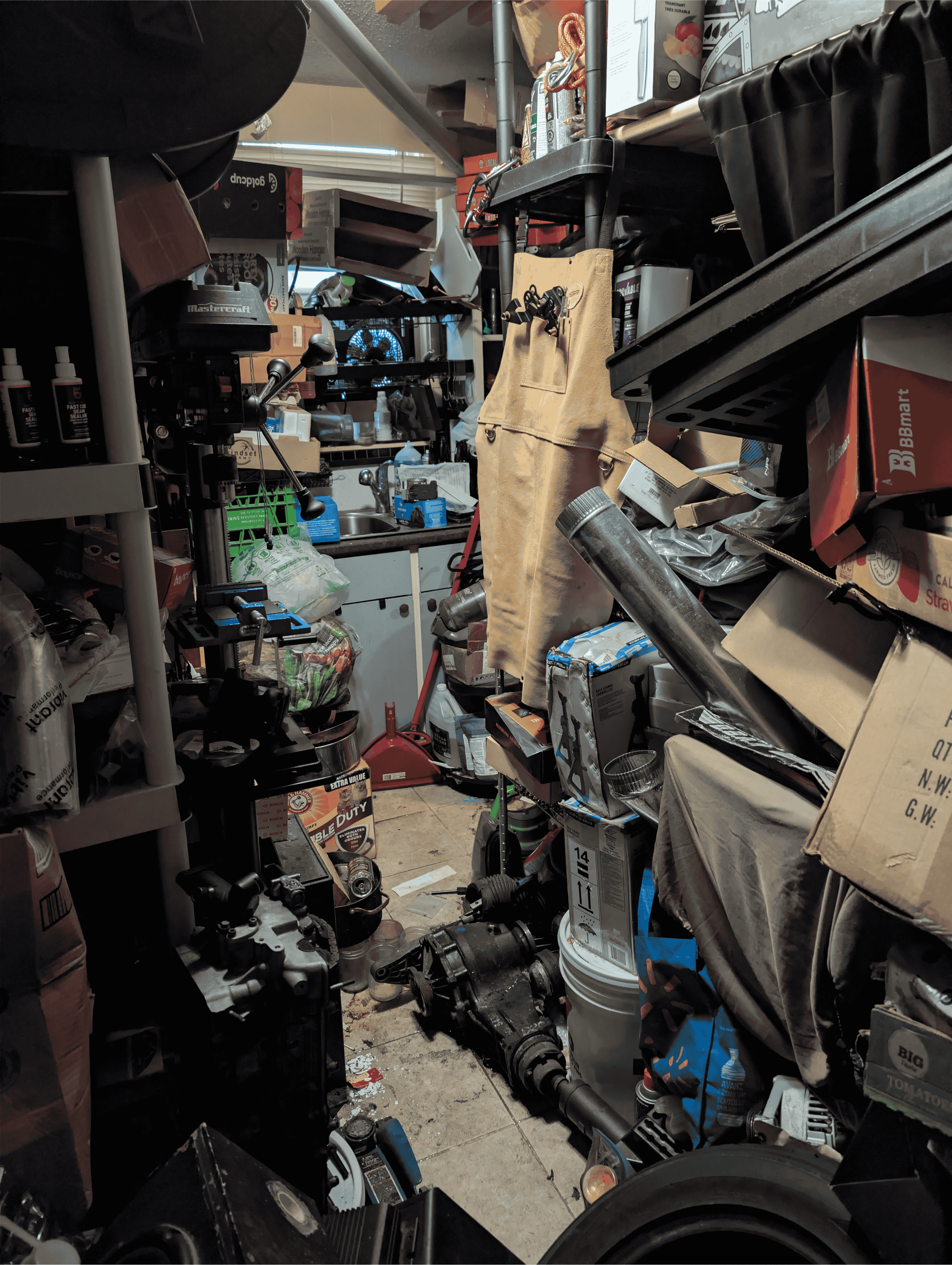 Kitchen filled with boxes, bags, tools, cleaning supplies, and household items.
